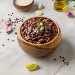 "Wooden bowl of chunky red sauce garnished with parsley, surrounded by garlic, shallots, lime, yogurt, olive oil, and peppercorns."